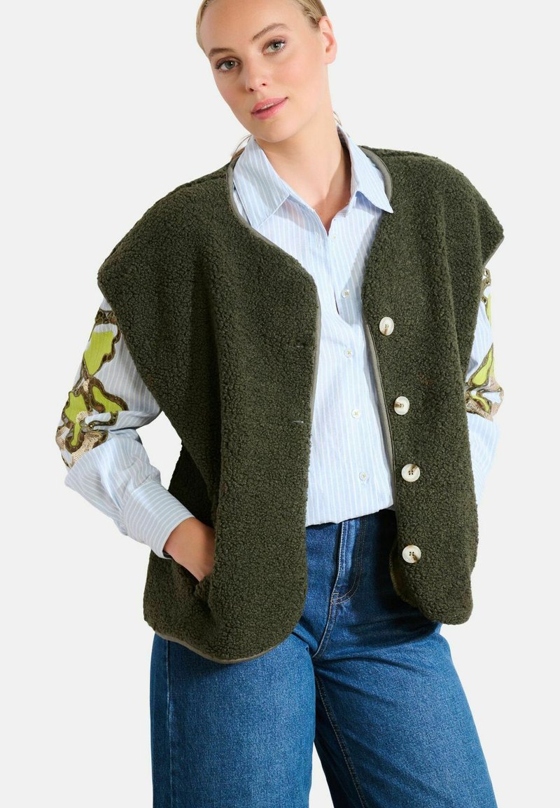 Groene fleece vest met knoopsluiting, oversized ontwerp, twee zijzakken en gemusterde mouwen met groene en bruine accenten.