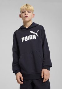 Jūras spēku kapuces džemperis mīkstā audumā ar lielu balto PUMA logo, priekšējo kangaroo kabatu un ribotām piedurknēm un apakšmalu.