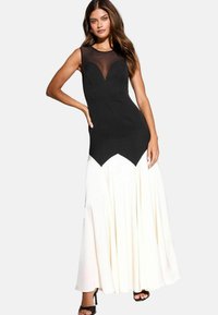 Rochie alb-negru cu un corset ajustat și fustă evazat�ă. Decolteu din plasă neagră transparentă, material inferior alb contrastant și design pliat.