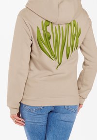 Felpa beige con una grande grafica verde "NEW YORK" sul retro, con polsini e orlo a costine e cappuccio regolabile con cordino.