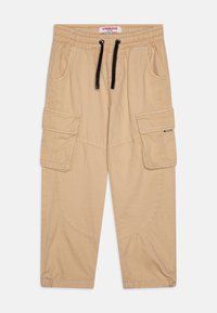 Pantalons cargo beige avec une taille élastique, cordon de serrage noir, poches latérales et poches à rabat sur les cuisses. Fabriqués en tissu cotonnade résistant.