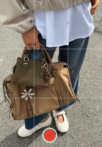 Due borse: una borsa di pelle marrone chiaro con sontuose frange laterali e una borsa più piccola di colore verde oliva. Entrambe presentano accessori in metallo e un portachiavi decorativo.