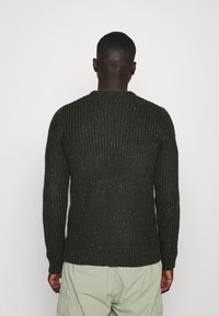 Dunkelgrüner, strukturiert gestrickter Pullover mit gerippter Optik, rundem Ausschnitt und langen Ärmeln, der dezente Sprenkel aufweist.