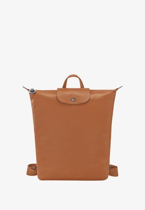 Brown leather backpack with a structured shape, top handle, adjustable straps, snap closure, and embossed logo detail on the front.