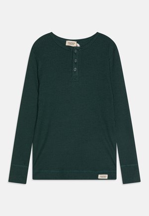 Dark green long-sleeve shirt with a ribbed texture, three button placket, and a tag with brand name stitched at the hem.