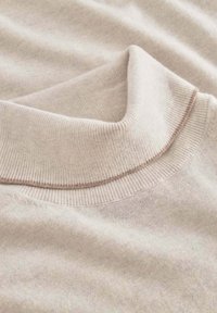 Hellbeiger Pullover mit einem gerippten Kragen. Weiche Textur, mit einem leicht kontrastierenden Streifen am Rand des Kragens und insgesamt glattem Stoff.