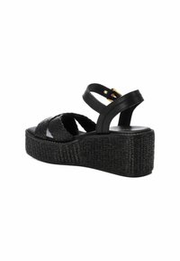 Sandalias de cuña negras con un diseño de tiras trenzadas, parte superior de cuero y una suela de plataforma texturizada. Presenta correas ajustables en el tobillo y acentos dorados.