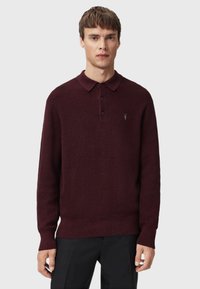 Burgundy sweater with a ribbed texture, long sleeves, and a polo collar. Features three buttons and a small emblem on the chest.
