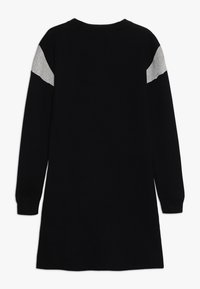 Černé dlouhé rukávy šaty vyrobené z měkkého pleteného materiálu. Obsahují šedé akcenty na ramenech a design s kruhovým výstřihem. Jednoduchý, rovný střih.