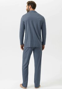 Marineblauw pyjamaset met lange mouwen en broek. Voorzien van een herhalend wit geometrisch patroon en een zachte stoftextuur.