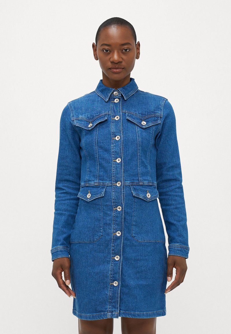 Denim obleka z gumbi spredaj, s točkovanim ovratnikom in dvema žepoma na prsih. Ima dolge rokave in prileganje v srednjem modrem odtenku.