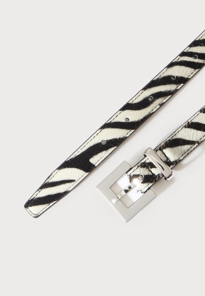 Ceinture en cuir à imprimé zèbre noir et blanc avec boucle rectangulaire argentée et trous de réglage sur fond blanc.