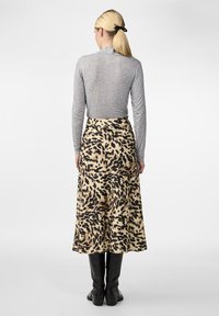 Grå langermet topp kombinert med et flytende, leopardmønstret skjørt i beige og svart. Glatt tekstur med midje lengde. Svarte støvler.