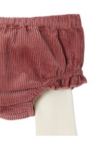 Rosa Rippstrick-Babyliegeschirre, die über weißen Rippstrick-Leggings getragen werden, mit elastischem Bund und Rüschen an den Beinausschnitten.