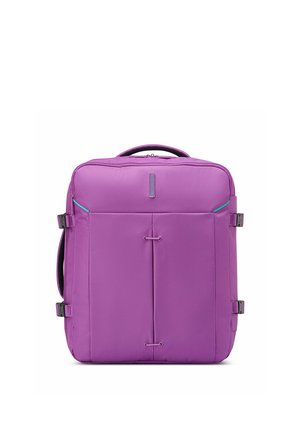 Square purple suitcase with top handle, front pocket, and side compression straps on a white background.