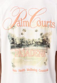 Hvit bomulls T-skjorte med grafisk trykk av palmer, tennisbaner og teksten "Palm Courts Pasadena" i korall- og oransjetoner.