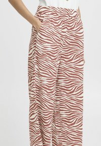 Pantaloni a gamba larga in un tessuto morbido caratterizzati da un motivo a strisce zebra bianco e marrone, con tasche laterali e una vita elastica.