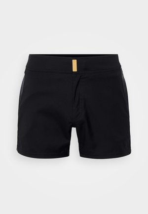 Pantalones cortos deportivos negros con un tejido texturizado, cintura elástica y una pequeña etiqueta dorada en la parte delantera. Largo corto con un diseño minimalista.