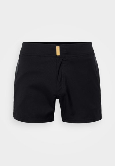 Pantalones cortos deportivos negros con un tejido texturizado, cintura elástica y una pequeña etiqueta dorada en la parte delantera. Largo corto con un diseño minimalista.