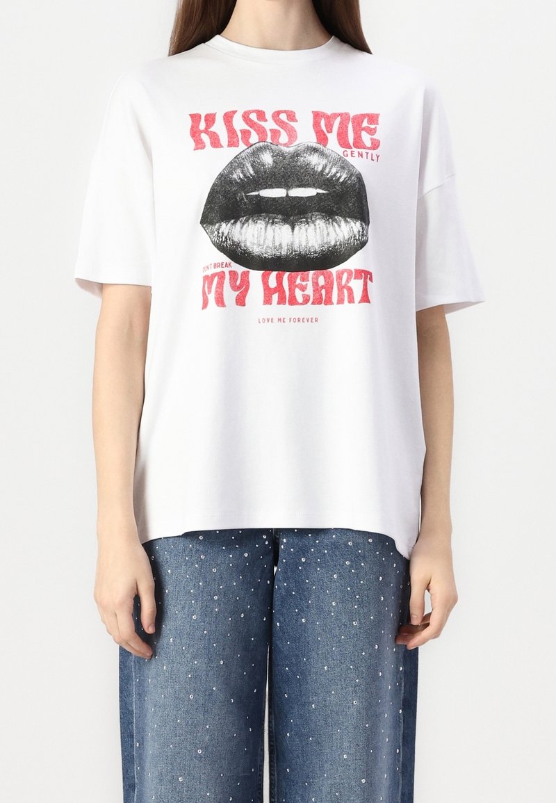 T-shirt bianco a maniche corte con una grande grafica di labbra nere e del testo rosso che recita "BACIOLE GENTILMENTE" e "IL MIO CUORE" in lettere grasse.
