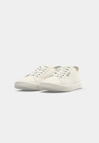 Hvite kanvas sneakers med rund tå, flat gummisåle og metalløye for snøring. Minimalistisk design uten mønstre eller synlig merkevare.
