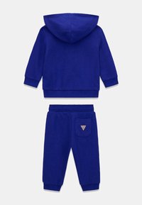 Blauw katoenen trainingspak met een gewatteerde jas met capuchon en joggingbroek, geribbelde boorden en een driehoekig logopatch op de achterzak.