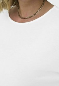 Top blanco de manga corta con escote redondeado y textura suave, combinado con un collar de cadena dorada con eslabones planos interconectados.