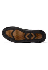 Zwarte sneakerzool met een gestructureerd rubberpatroon en een honingraatdesign. Heeft een bruine accent in het midden en een duidelijk DC-logo.