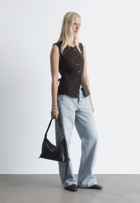 Brauner ärmelloser Oberteil mit Knopfverschluss, blaue weit geschnittene Jeans und eine schwarze geflochtene Handtasche. Glatte Textur, taillierte Passform und minimalistisches Design.