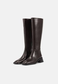 Stivali in pelle marrone al ginocchio con una texture liscia, punta quadrata e tacco basso a blocco. Presentano una zip laterale per una facile vestibilità.