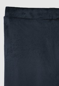 Tessuto morbido di colore blu navy con una texture a costine, caratterizzato da una vita con strisce orizzontali. La forma generale è rettangolare e liscia.