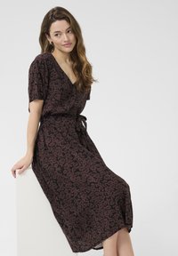Schwarzes Kleid mit Blumenmuster, kurzen Ärmeln, V-Ausschnitt, Gürtel in der Taille und fließender Silhouette. Der Stoff wirkt weich und leicht.