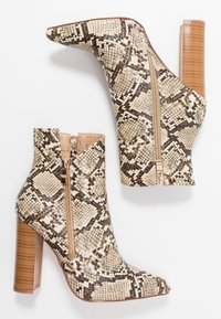 Stivaletti alla caviglia a motivo serpente in faux leather beige e marrone, con punta affusolata, tacco a blocco di media altezza e chiusura con zip laterale.