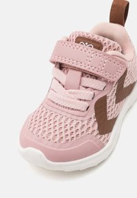 Rosa treningssko med pustende mesh-overdel, forsterket tåhette, teksturerte overleiringer, borrelåsrem og hvit gummisåle.