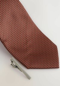Burgundská tkaná kravata s textúrovaným vzorom, v páre so striebornou kravatovou sponou s ryhovaným povrchom a lesklým dokončením.