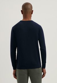 Maglione blu navy a maniche lunghe con collo rotondo, in material leggero a maglia, con polsini aderenti e orlo standard. Design minimalista e versatile.