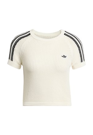 Kremowy prążkowany crop top z teksturowanej dzianiny, krótkie rękawy i czarne paski na ramionach. Z małym czarnym logo.