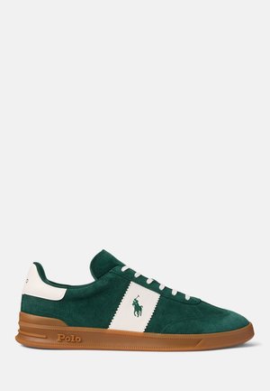 Zapatilla de ante verde oscuro con detalles en piel blanca, suela marrón, cordones blancos y logotipo Polo en el lateral y en el talón.
