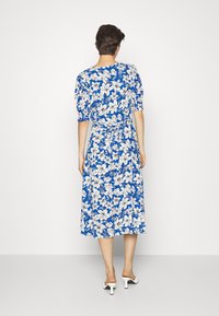 Vestido midi floral com fundo azul e flores brancas, mangas curtas abalonadas e um laço na cintura. Tecido suave e barra godê.