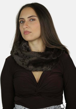 Jonge vrouw met lang bruin haar, gekleed in een donkerbruin gedraaid topje en een dikke, donkerbruine oneindige faux-fur sjaal.