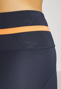 Marina träningsleggings med ett orange horisontellt rand och präglad logotyp. Slät, elastisk tyg med en åtsittande design och ren sömnad.