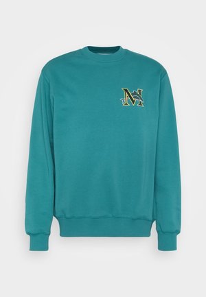 Blågrøn crewneck-sweatshirt med lange ærmer og delfinlogo, der krydser et guldindrammet bogstav "N" på venstre side af brystet.