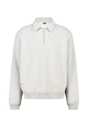 Lichtgrijze pullover met lange mouwen, half-ritskraag en geribde manchetten, met een klein wit label bij de zoom aan de linkerkant.