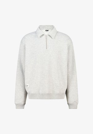 Lichtgrijze pullover met lange mouwen, half-ritskraag en geribde manchetten, met een klein wit label bij de zoom aan de linkerkant.