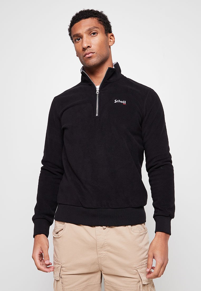 Pullover in pile nero con zip a un quarto sul davanti, polsini e orlo a coste; presenta un piccolo logo rosso sul petto a sinistra.