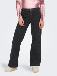 Crne široke traperice s visokim strukom, s pet džepova i suptilnim izbljeđenjem. Uparene s crveno-bijelim prugastim topom.