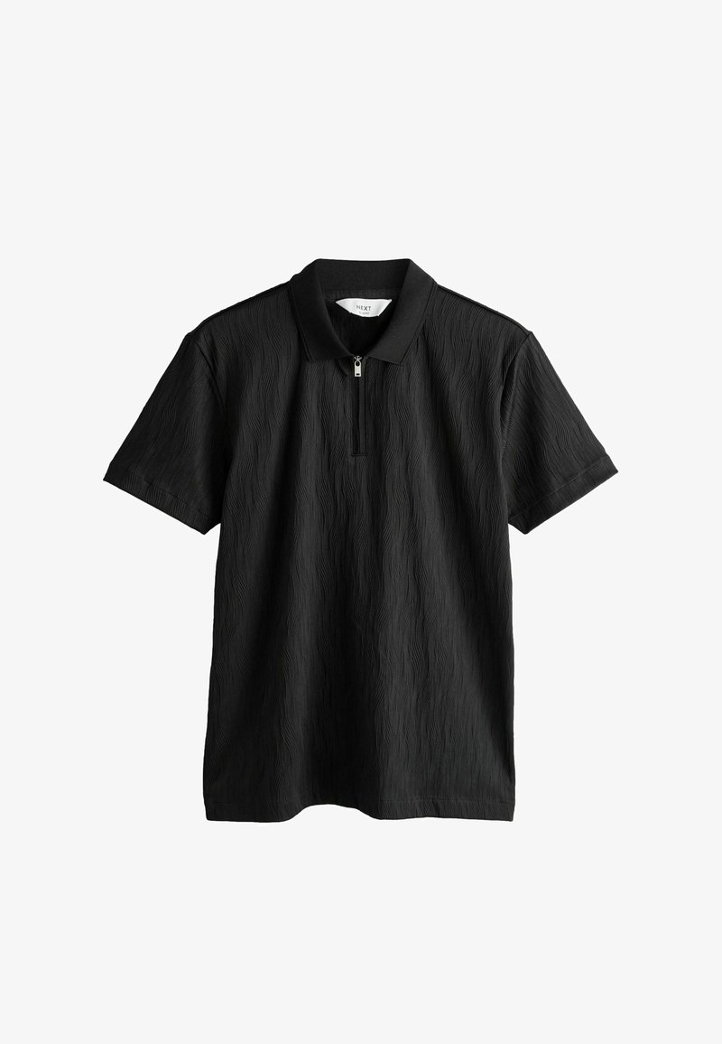Polo noir à manches courtes avec motif ondulé texturé, fermeture éclair à l'avant, col et étiquette indiquant "NEXT".