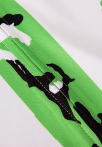 Camo-gepatroniseerd stof met zwart, wit en groene kleuren en een gladde textuur; stiksels langs de naad.