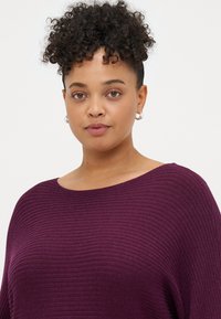 Lila geripptes Sweatshirt mit weitem Ausschnitt und langen Ärmeln, aus einem strukturierten Stoff, der dem Design Dimension verleiht.