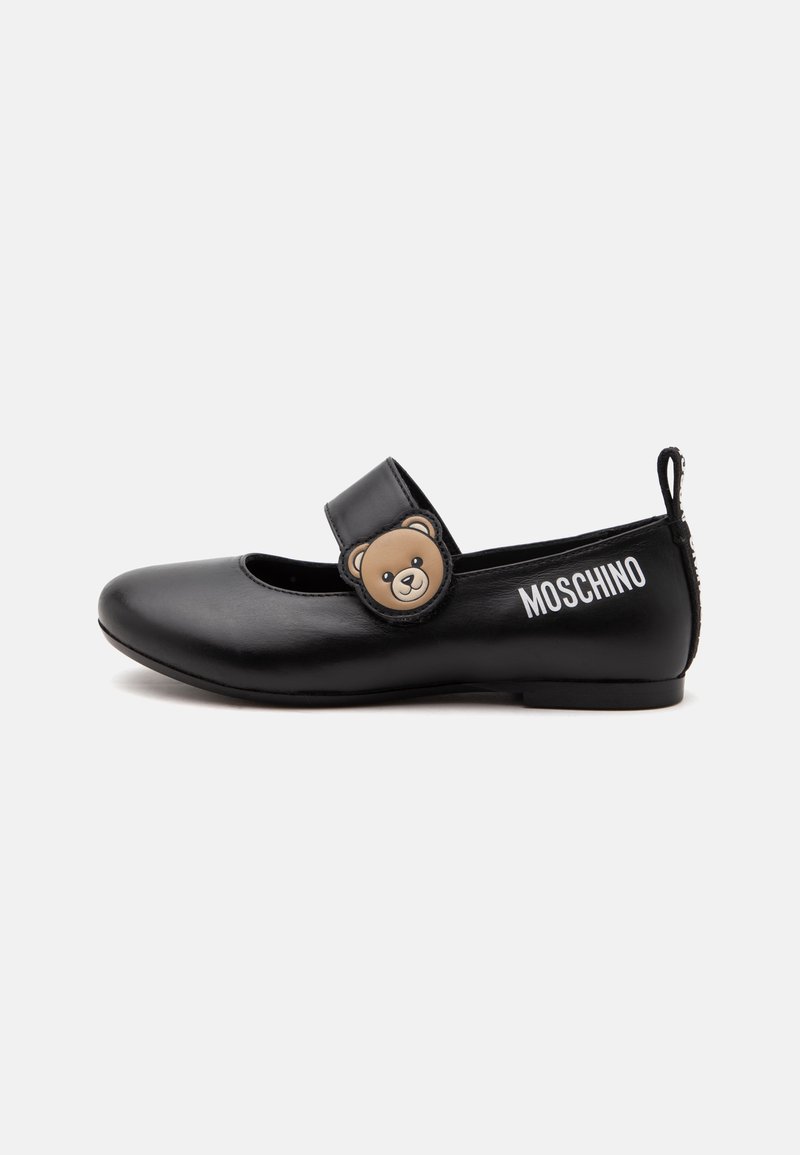 Chaussure Mary Jane noire avec une décoration en forme d'ours en peluche sur la bride et « Moschino » imprimé sur le côté, semelle plate et languette à l'arrière.
